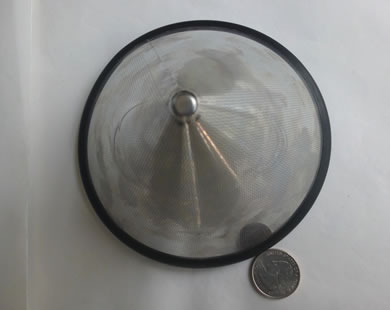 A cone filter with the sharp bottom facing up is beside a metal coin.