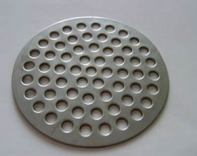 A round perforated stainless steel filter disc.