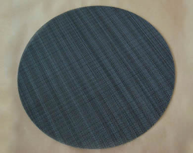 A round twill weave black wire cloth filter disc.