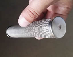 A hand holds a oblique cylinder filter with metal cap.