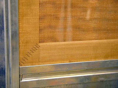 A piece of brass window screen is installed on the aluminum frame.