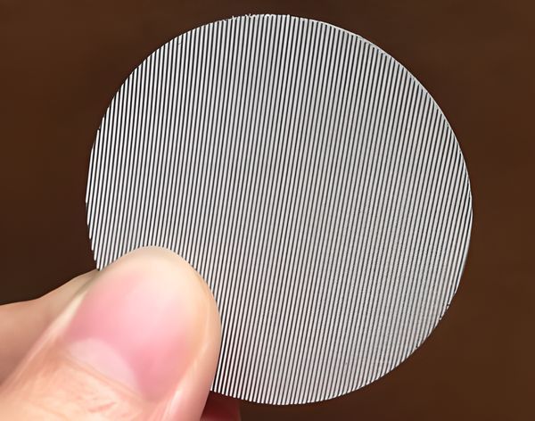 Two fingers pinch a dutch weave type filter disc.