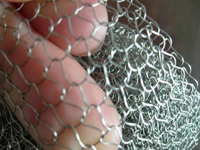 A hand is holding a piece of round wire knitted mesh.